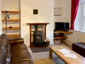 salon z kanapą i piecem opalanym drewnem w obiekcie Croft Cottage w mieście Braithwaite