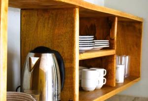 - une armoire en bois avec une cafetière et des assiettes dans l'établissement Maryam Garden Apartments & Villa, à Bwejuu