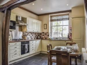 een keuken met witte kasten en een tafel en een raam bij Yew Tree Cottage in Windermere