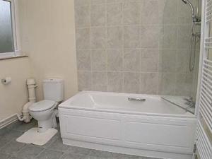 y baño con bañera blanca y aseo. en The Gatehouse en Hooke