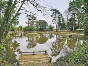 un pequeño estanque con un muelle de madera en un parque en The Gatehouse en Hooke