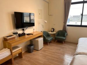 een kamer met een bureau, een televisie en een bed bij Chia Lung Gold Coast Homestay in Hu-nei