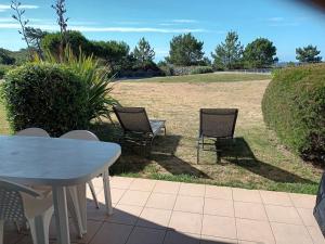 une table et des chaises assises sur une terrasse avec un champ dans l'établissement Appartement forever, à Les Sables-dʼOlonne