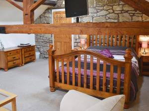 a bedroom with a wooden bed and a tv at The Stables in Ball