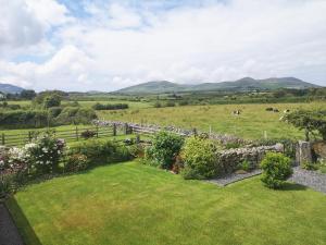 a garden with a stone fence and flowers in a field at Beudy Isaf in Llangybi