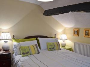 a bedroom with a bed with green and white pillows at Toms Cottage in Dalton in Furness