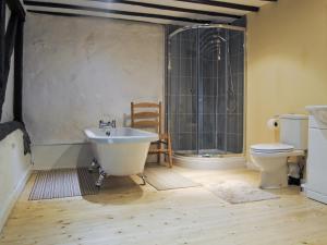 a bathroom with a tub and a toilet and a sink at Hirros Hall Longhouse in Llanerfyl