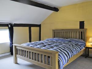 a bedroom with a bed with a blue and white comforter at Hirros Hall Longhouse in Llanerfyl