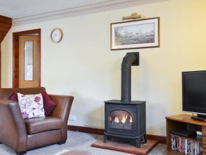 a living room with a stove and a chair and a television at Mill Pond Cottage in Cromford