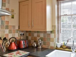 a kitchen with wooden cabinets and a counter top at Mill Pond Cottage in Cromford