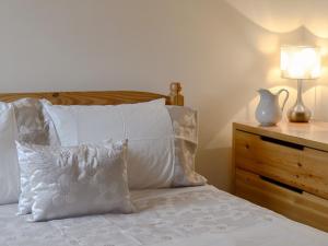 クロムフォードにあるMill Pond Cottageのベッドルーム1室(白い枕とランプ付きのベッド1台付)