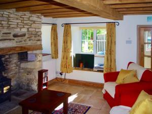 a living room with a red couch and a fireplace at Ivy Cottage in Chedworth