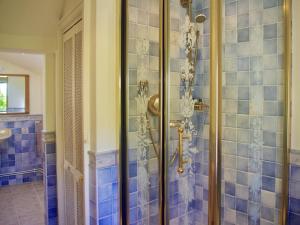 ein Bad mit einer Dusche und blauen Fliesen in der Unterkunft Ivy Cottage in Chedworth