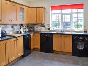 a kitchen with wooden cabinets and a black dishwasher at Bay House in Filey