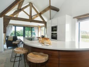 a kitchen with a white counter top and wooden stools at Puddledock Piggery in Berkley