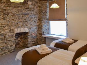 two beds in a room with a stone wall at Rosetta Apartments - Ocean Mist in Newquay