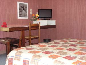 a bedroom with a bed and a desk with a television at Hotel du Parc in Thonac +34 photos