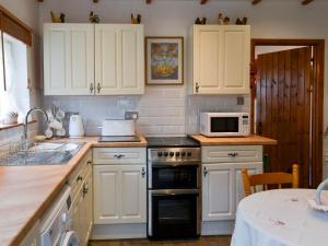 a kitchen with white cabinets and a stove top oven at Alpine Lodge in Burgh le Marsh