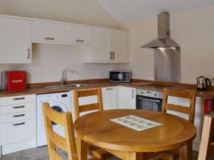 a kitchen with a wooden table and a kitchen with white cabinets at The Parlour in Normanton on Trent