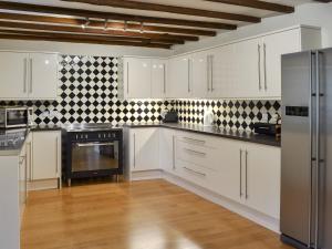 a kitchen with white cabinets and black appliances at The Old Stables in Standon