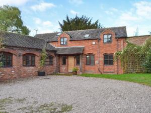 a brick house with a gravel driveway in front of it at The Old Stables in Standon