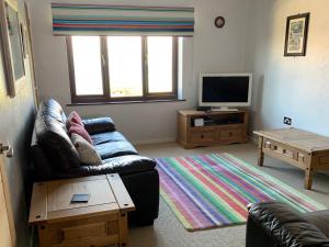 sala de estar con sofá y TV de pantalla plana en Sailfish en Benllech
