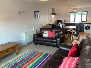 sala de estar con sofá de cuero y mesa en Sailfish, en Benllech