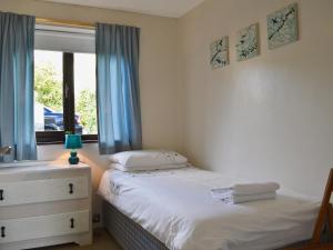 a bedroom with a bed and a window with blue curtains at Sailfish in Benllech