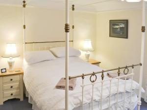 a bedroom with a four poster bed and two lamps at Poppies in Blakeney
