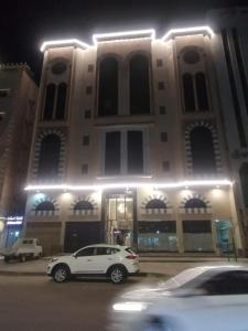 a white car parked in front of a building at night at فندق النيم in Al ‘Awālī
