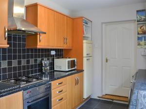 uma cozinha com armários de madeira e um micro-ondas branco em Naters Apartment em Cullercoats