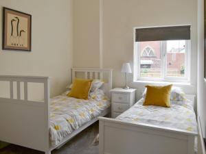 a bedroom with two beds and a window at Naters Apartment in Cullercoats