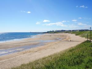 a beach with people walking on the sand and the ocean at Naters Apartment in Cullercoats