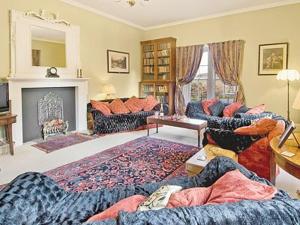 a living room with two couches and a fireplace at Lochside Stable Hse in Town Yetholm