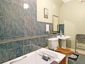 a bathroom with a tub and a toilet and a sink at Lochside Stable Hse in Town Yetholm