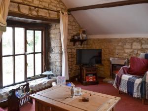 a living room with a table and a tv at Weycroft Hall Cottage in Axminster