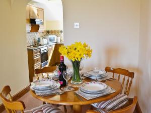 a dining room table with plates and a vase of yellow flowers at Owl Barn in Burmarsh