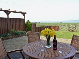 a wooden table with a bottle of wine and flowers on it at Owl Barn in Burmarsh