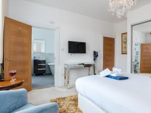 a white bedroom with a bed and a tv at Babbacombe Bay, Torquay in Torquay