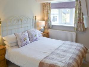 Un dormitorio con una cama blanca con almohadas y una ventana en Littlecroft, en Alnmouth