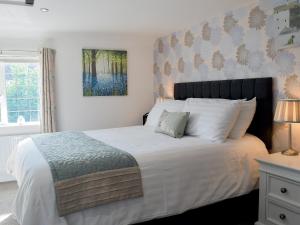 a bedroom with a large bed with white sheets at Little Willows in Bradenham