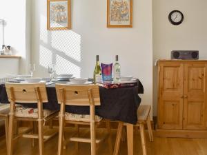 a dining room table with chairs and a bottle of wine at Biskey Howe Cottage in Bowness-on-Windermere