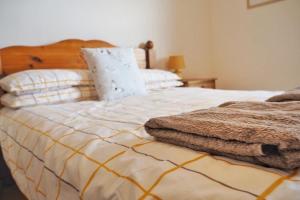 um quarto com uma cama com um cobertor branco e amarelo em Woodworth Cottage em Barnoldswick