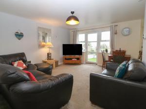 a living room with two leather couches and a flat screen tv at Beach View in Benllech