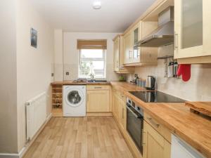 a kitchen with wooden cabinets and a washer and dryer at Beach View in Benllech