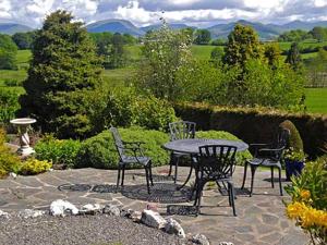 a patio with four chairs and a table with a view at Drumlin in Hawkshead