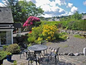 a patio with a table and chairs and flowers at Drumlin in Hawkshead