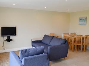 uma sala de estar com um sofá, cadeiras e uma mesa em Freefolk Cottage em Polzeath