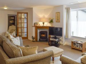 a living room with a fireplace and a tv at Beech Ghyll in Grasmere