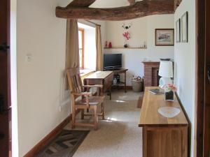 a living room with a table and a desk at Garden Cottage in Hasfield